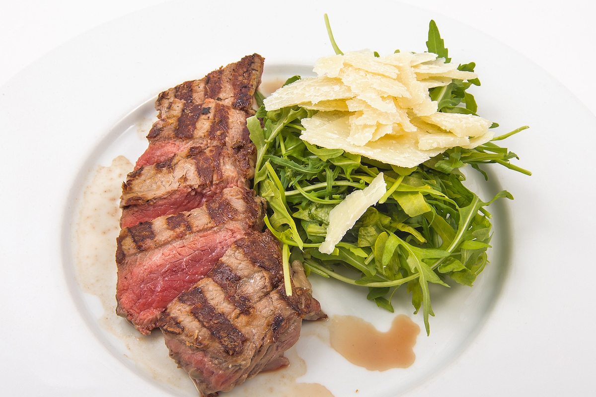 Geschnittenes Rindfleischsteak mit Rucola, gehobeltem Parmesan und Rosmarinkartoffeln
